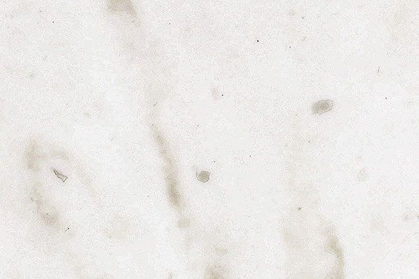 Off-white paper with subtle, irregular light brown stains and imperfections.