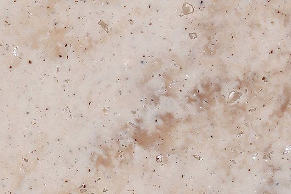 Beige and tan travertine stone surface with small dark specks and irregular patterns.