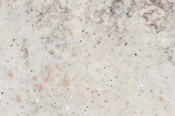 Cream-colored travertine with speckled markings and darker splotches across the top.