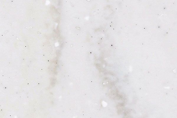 White marble surface with subtle gray veining and small dark specks.