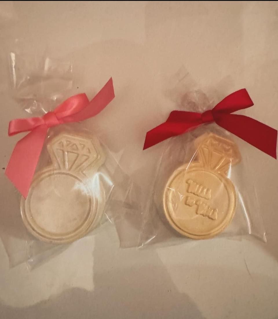 Two gold-toned medal favors in clear bags, each tied with a red bow