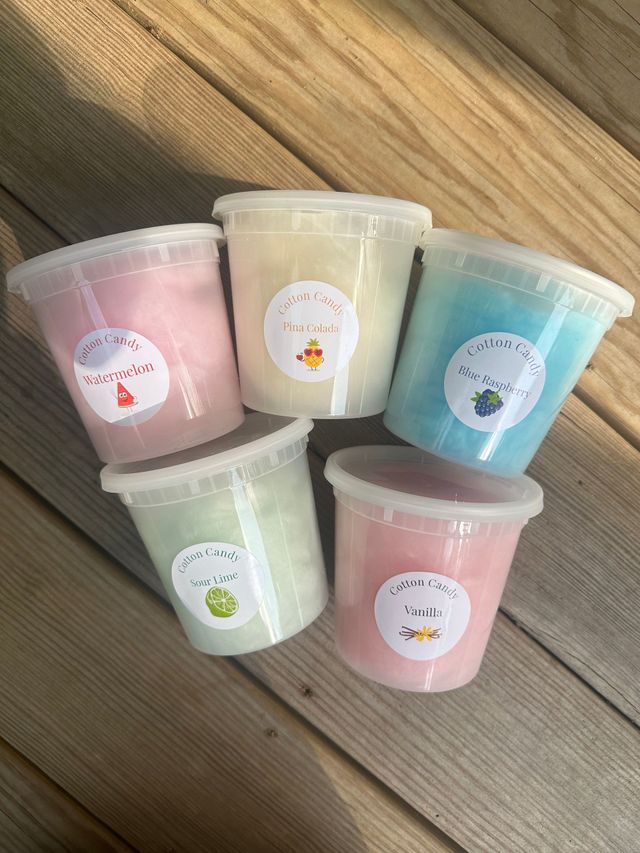 Five pastel-colored drink cups arranged on a wooden floor, each with a fruit label.