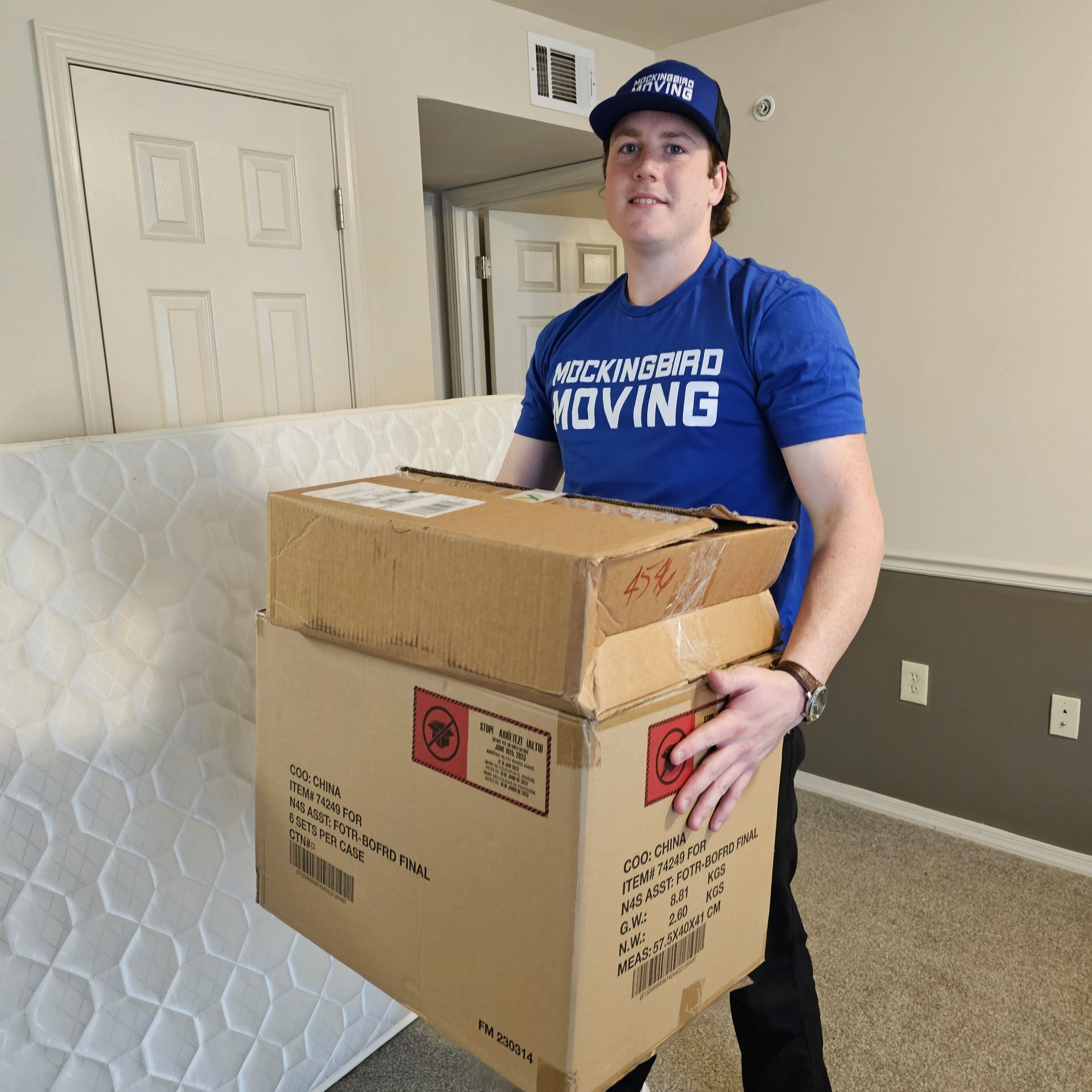 Two Men Are Moving A Couch In A Living Room - Fayetteville, AR - Mockingbird Moving