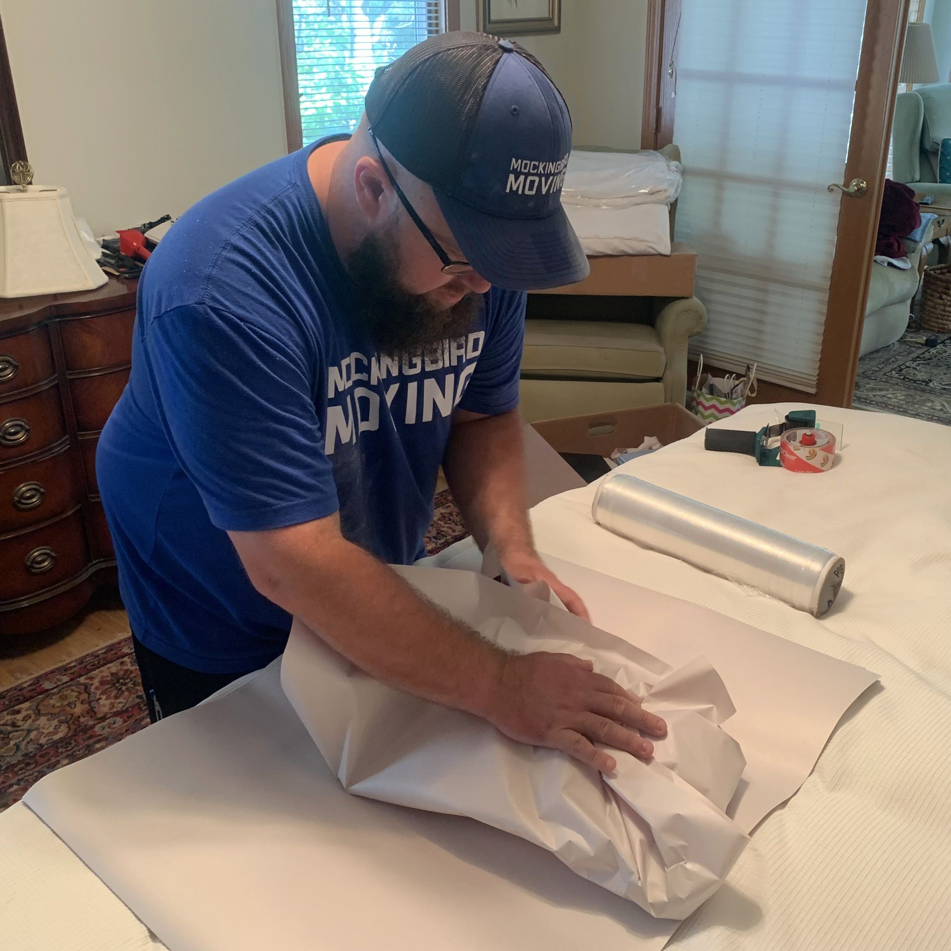 A Man Is Taping A Box With Tape In A Warehouse - Fayetteville, AR - Mockingbird Moving