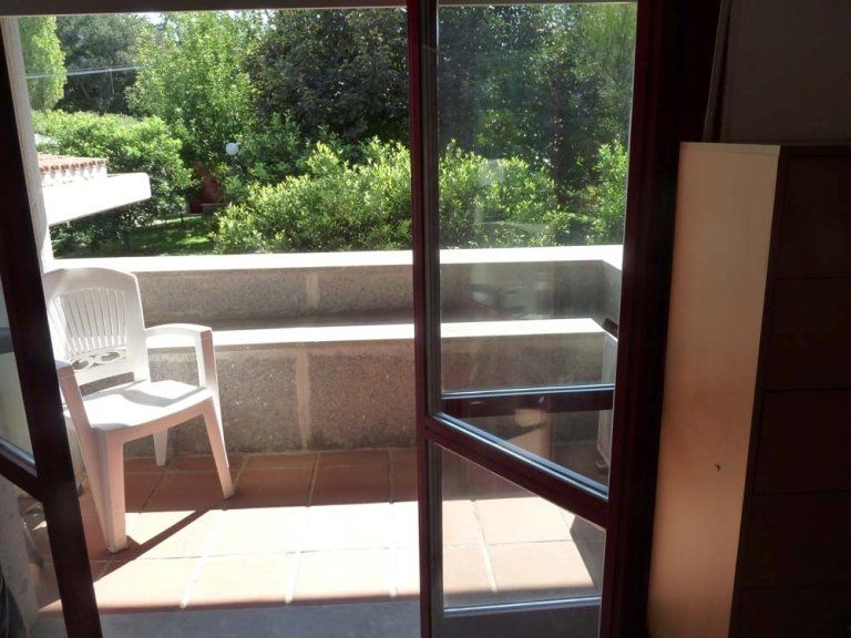 Una porta scorrevole in vetro conduce ad un balcone con sedia