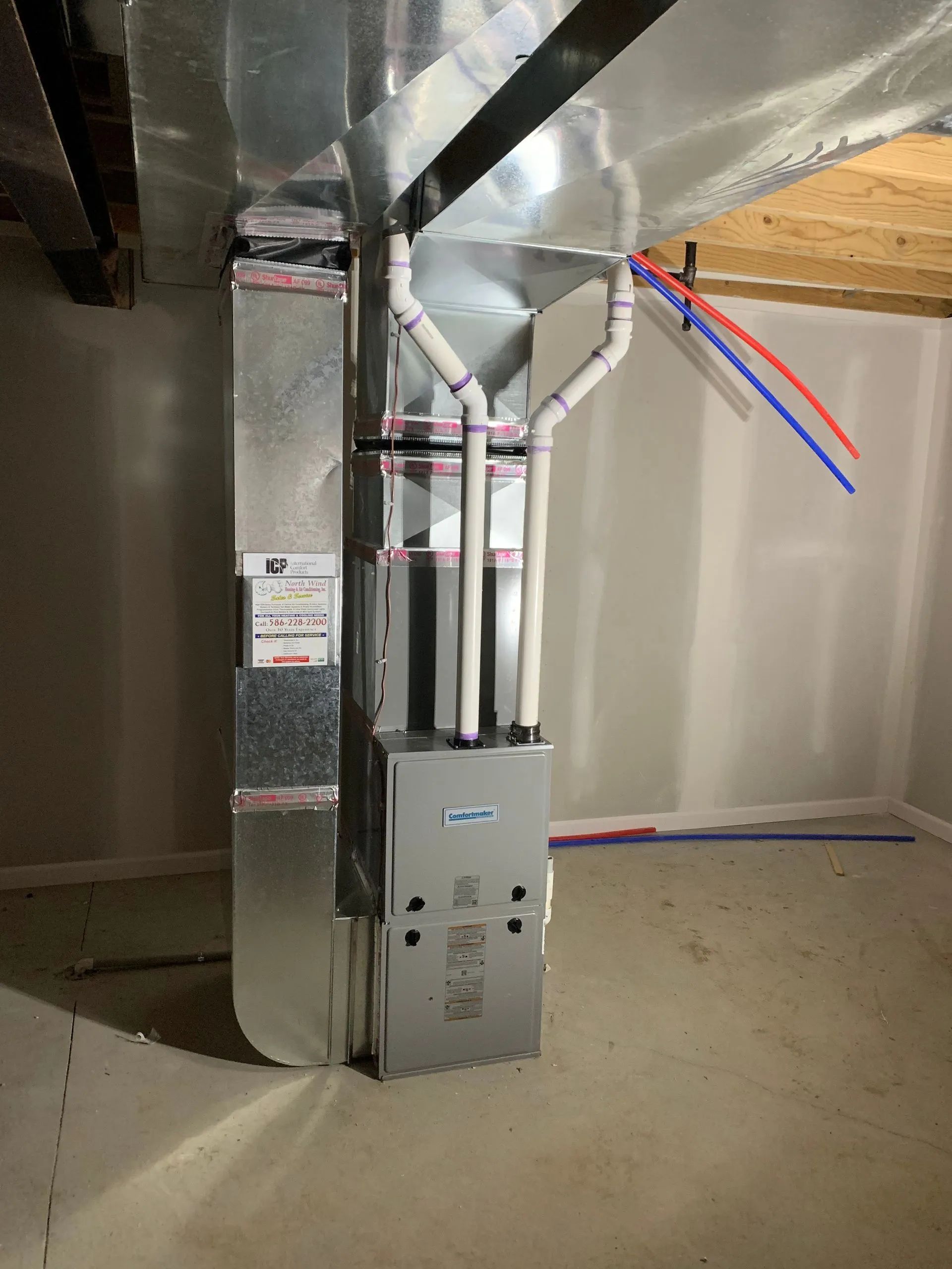 Furnace with ductwork and plumbing pipes in a finished basement.