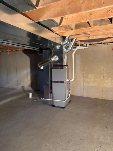 Furnace system with a humidifier in a utility space. Silver metal with white and gray pipes.
