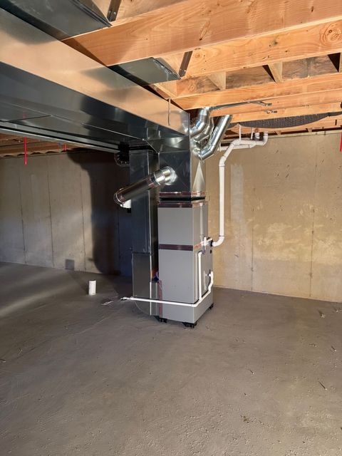 Furnace system with a humidifier in a utility space. Silver metal with white and gray pipes.