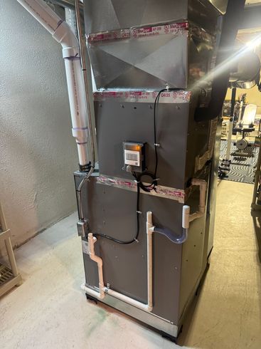 Gray Rheem water heater with red and black pipes in a utility room.