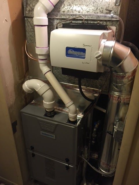 Furnace system with a humidifier in a utility space. Silver metal with white and gray pipes.