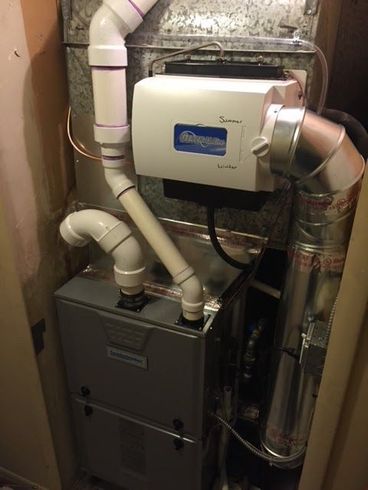 Furnace system with a humidifier in a utility space. Silver metal with white and gray pipes.