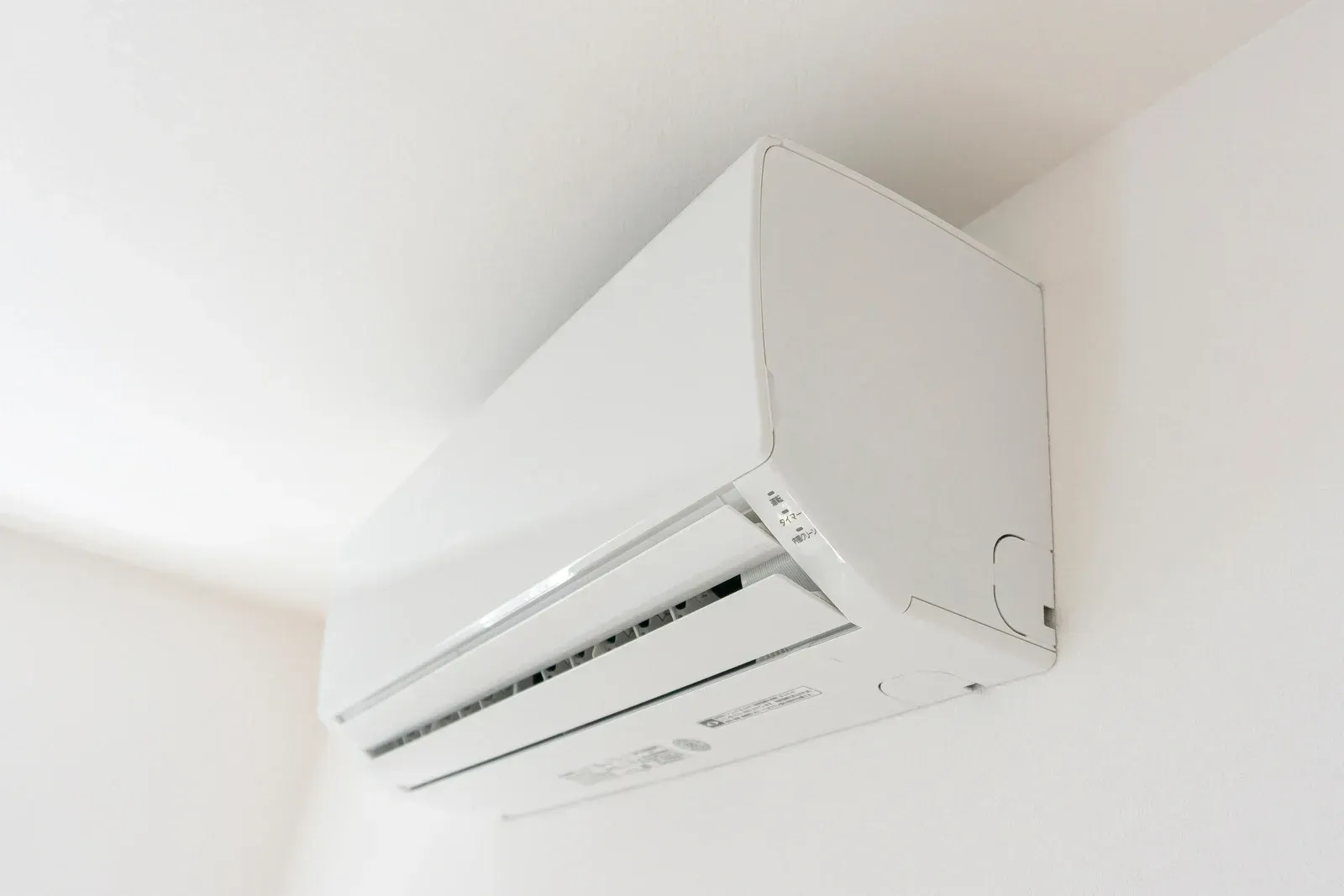 White wall-mounted air conditioning unit on a white wall.