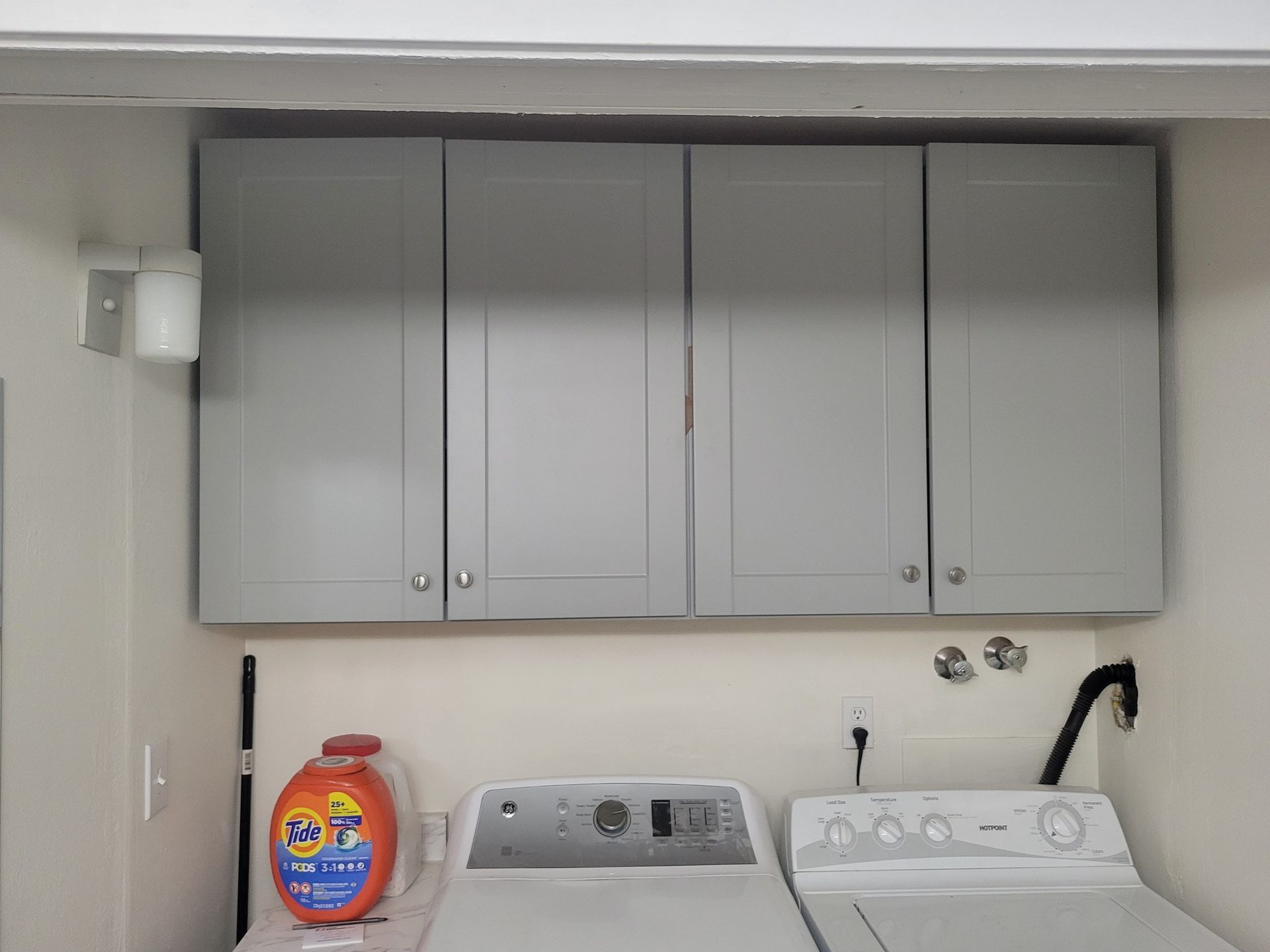 Laundry room with gray cabinets, washing machine, and detergent.