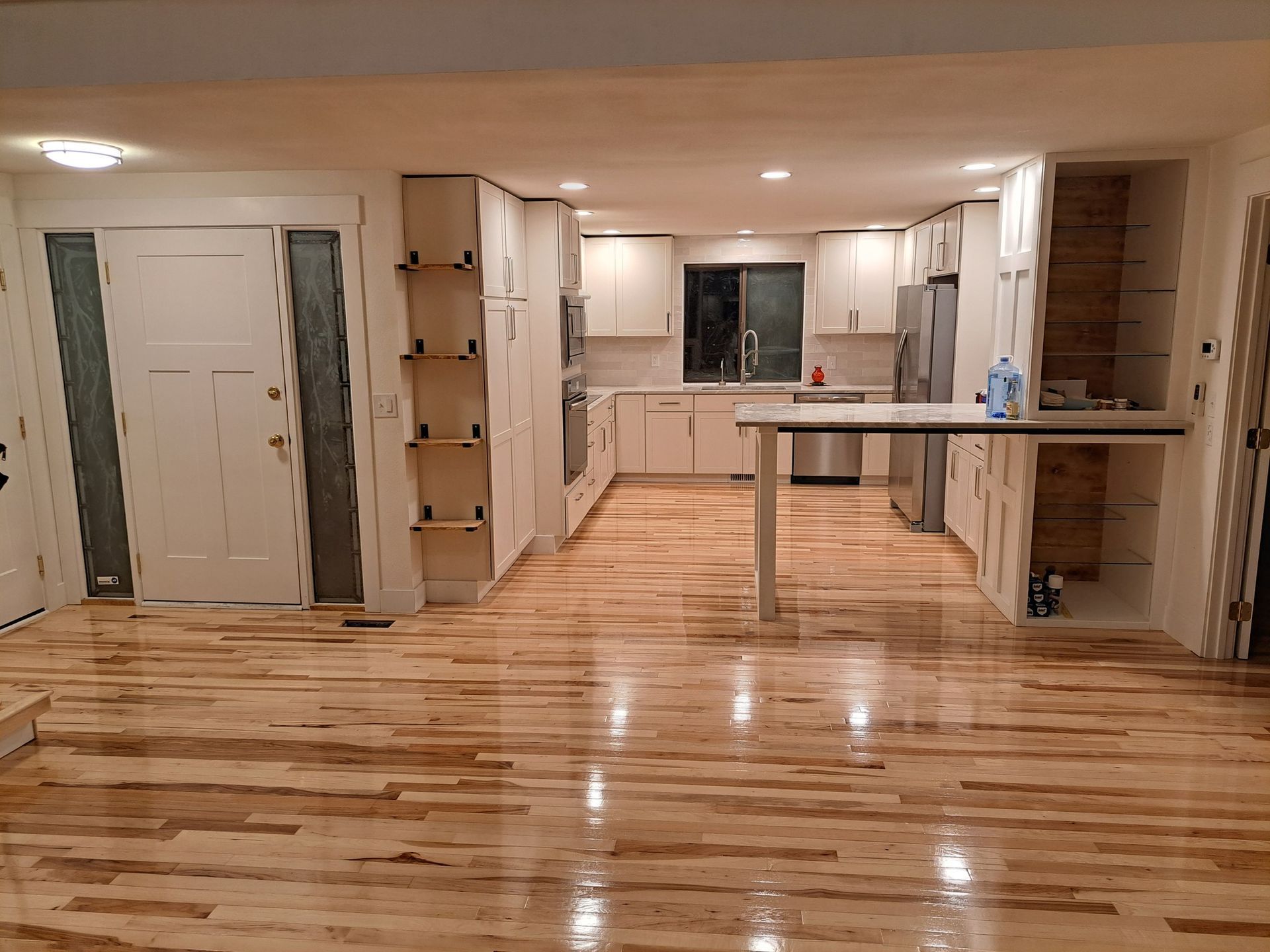 Newly renovated kitchen with light wood floors, white cabinets, and a stainless steel island.