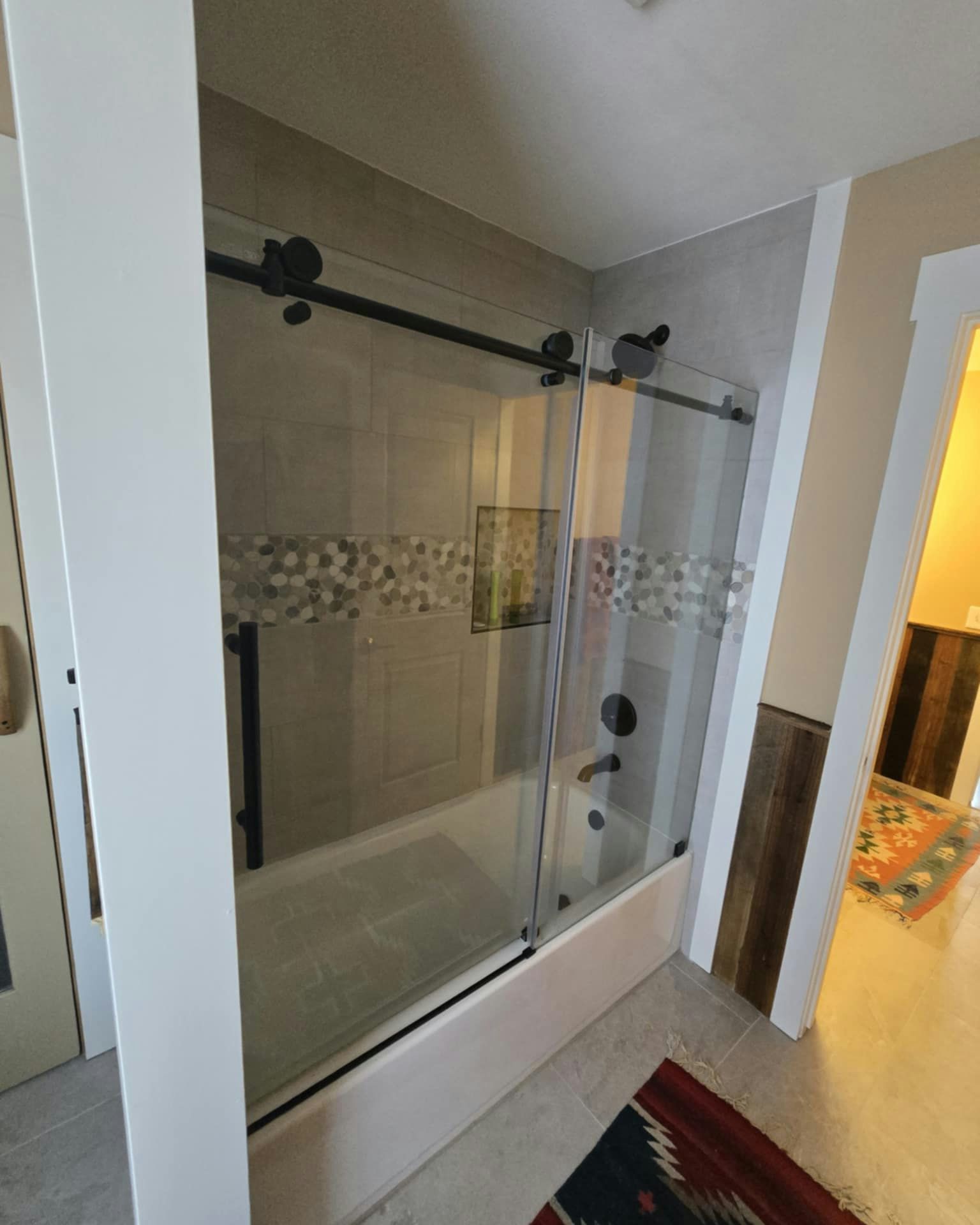 Shower with sliding glass doors and black hardware.