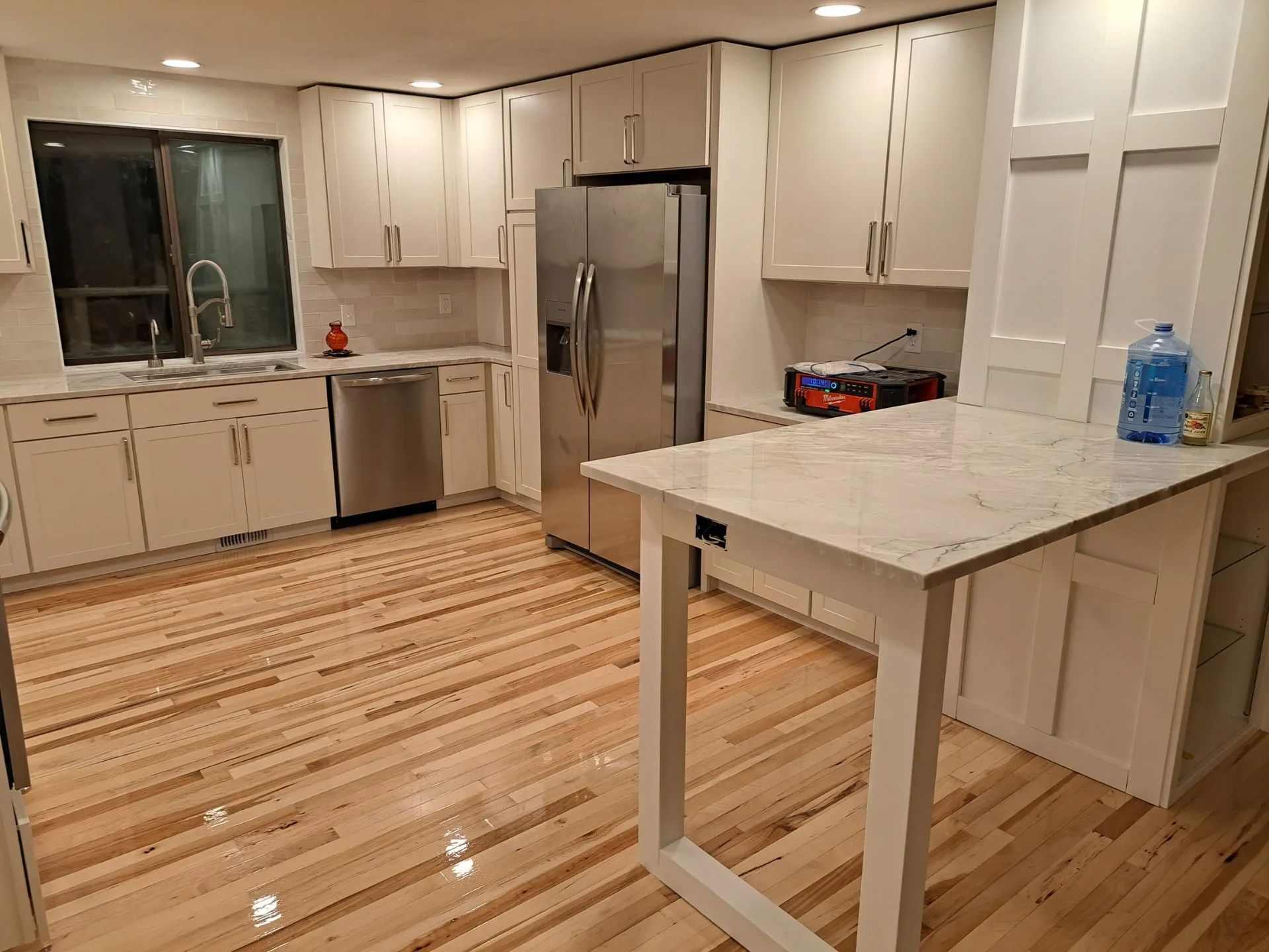 Modern kitchen with gray and white cabinets, wood countertop, built-in appliances, and recessed lighting.