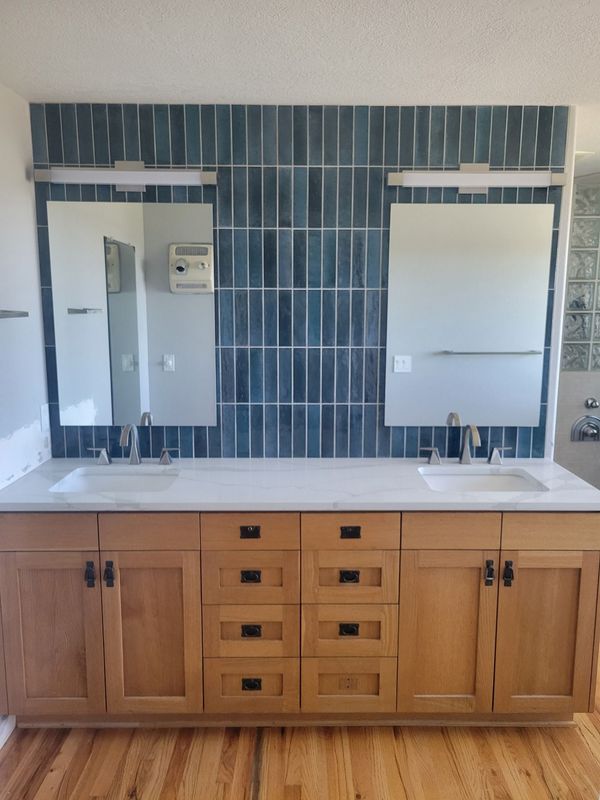 Laundry room with gray cabinets above washing machine and dryer. Tide detergent sits on machine.
