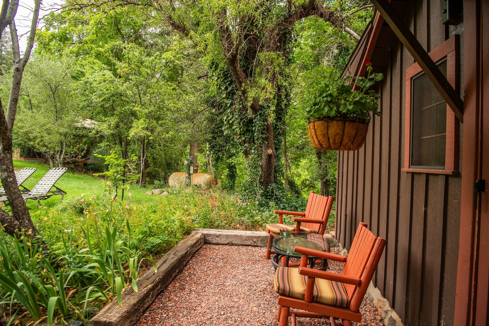 Two orange chairs on a porch overlooking a lush green garden.