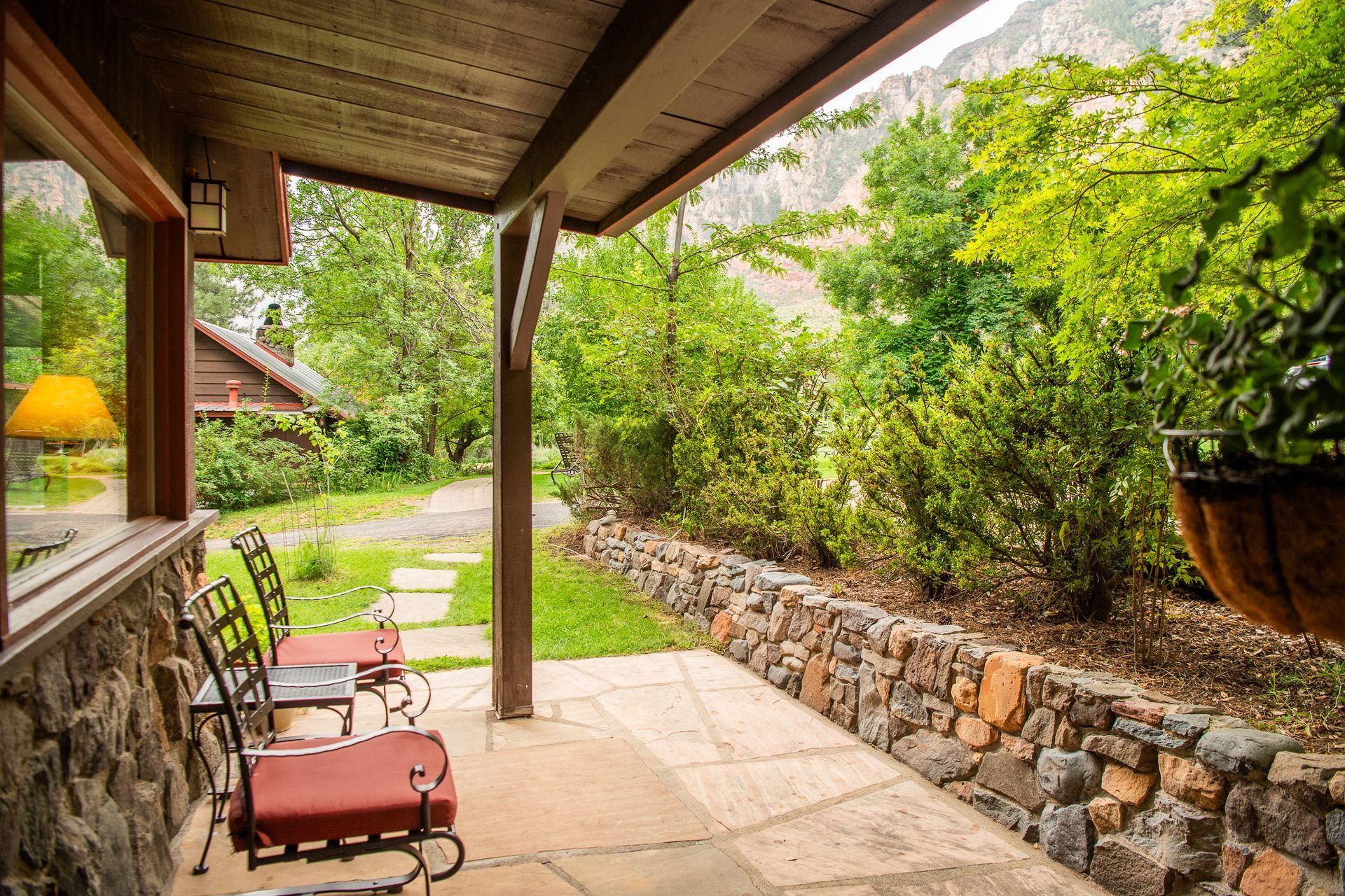 Porch with seating overlooking a lush, stone-walled garden.