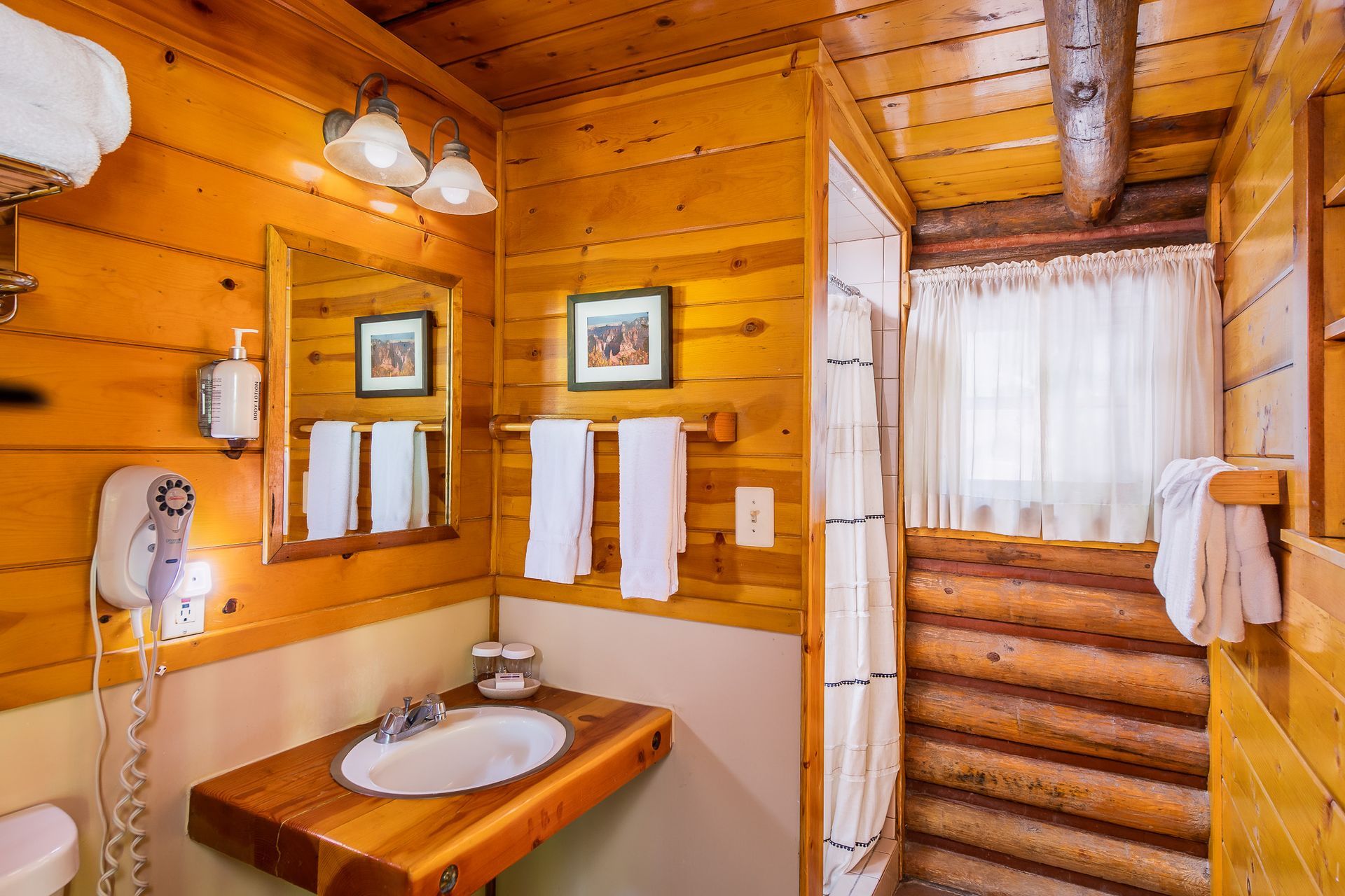 Wooden cabin bathroom with sink, mirror, and shower curtain.