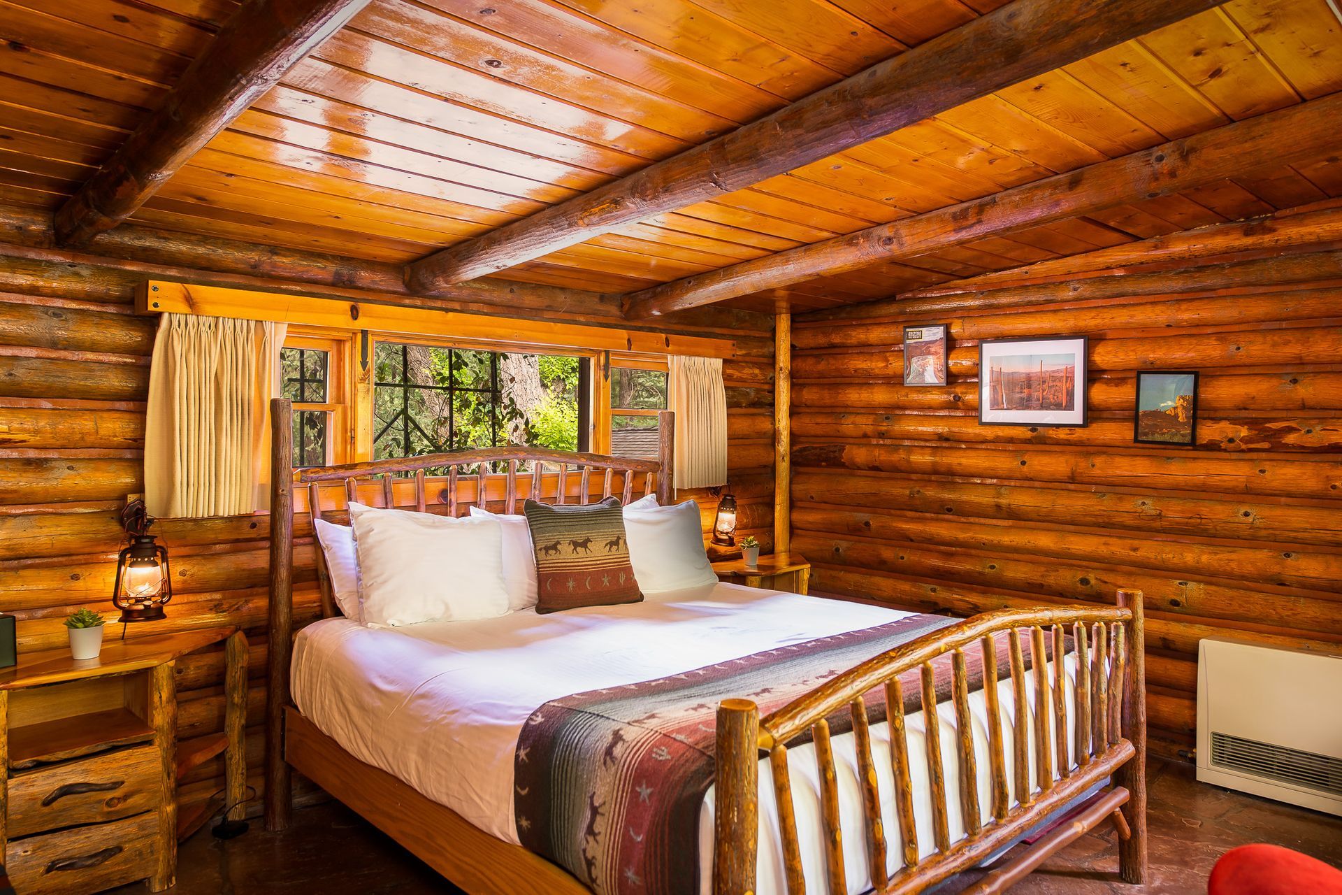 Cozy log cabin bedroom with a wooden bed, nightstand, and a window with sunlight.