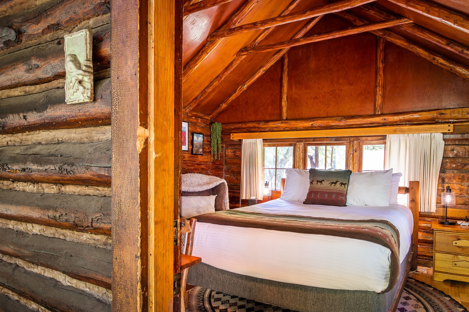 Cozy log cabin bedroom with bed, wooden beams, and a small window.