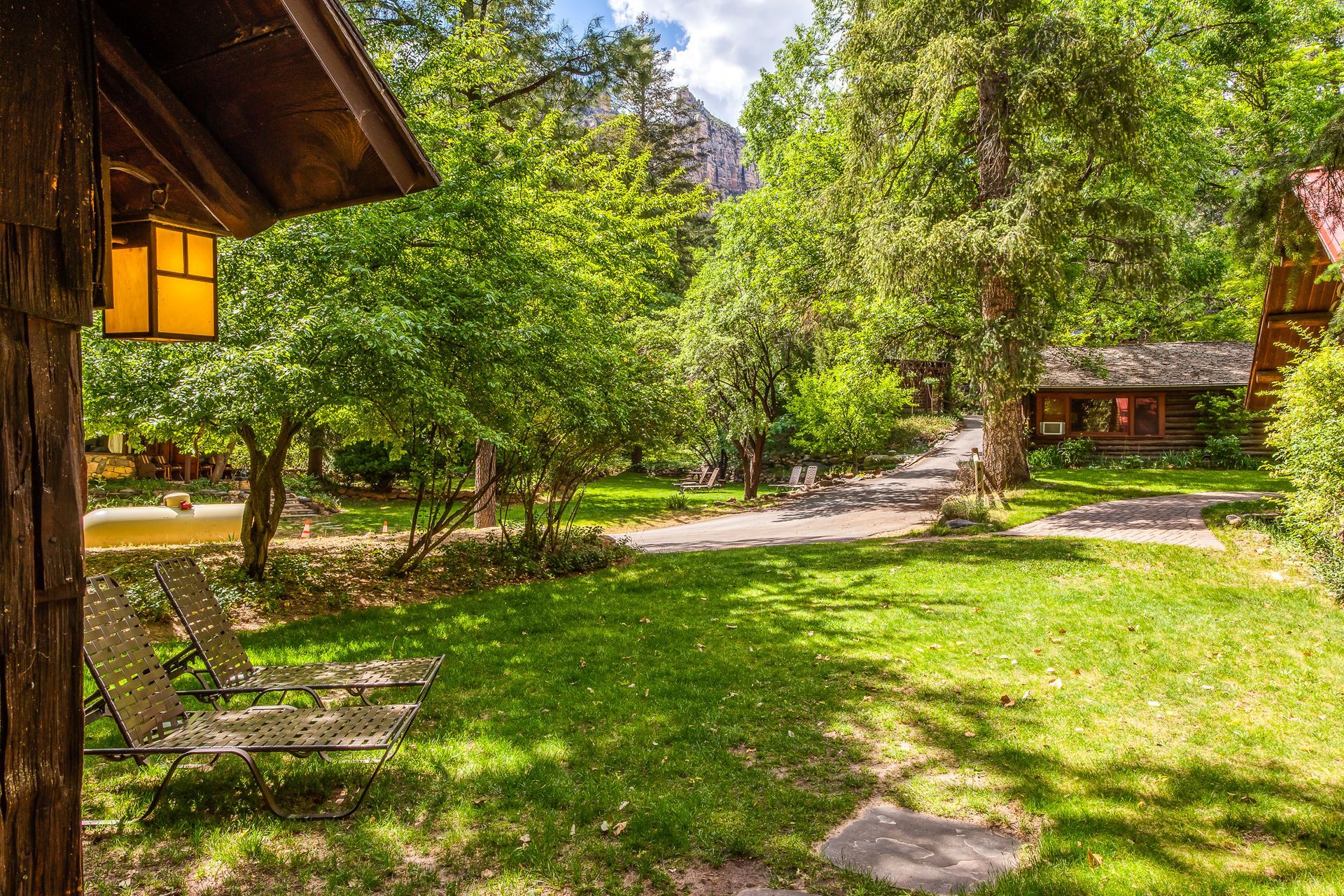 Lush green yard with chairs, trees, and cabins. Sunny day.