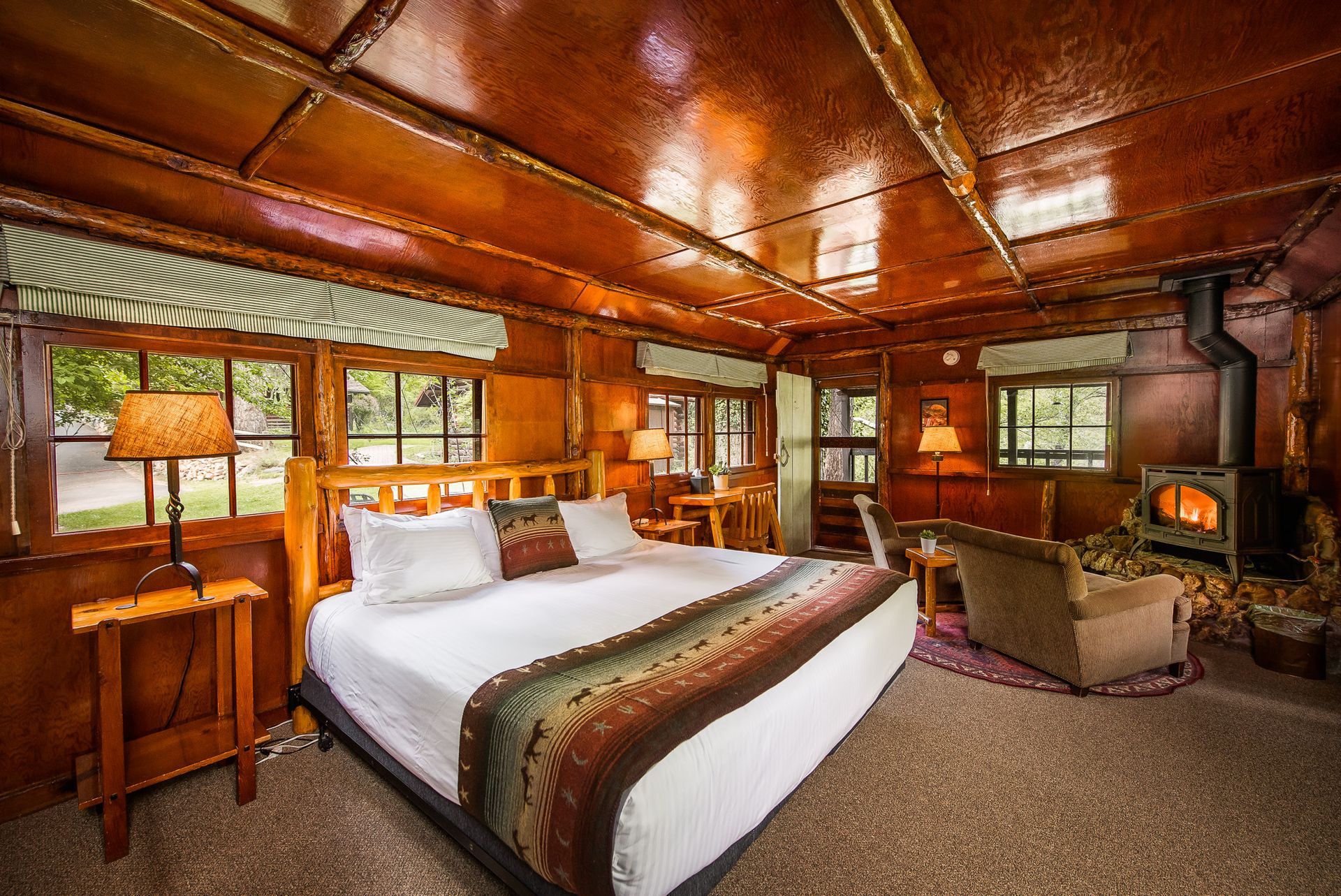 Cozy cabin bedroom with a large bed, fireplace, and wood paneling.