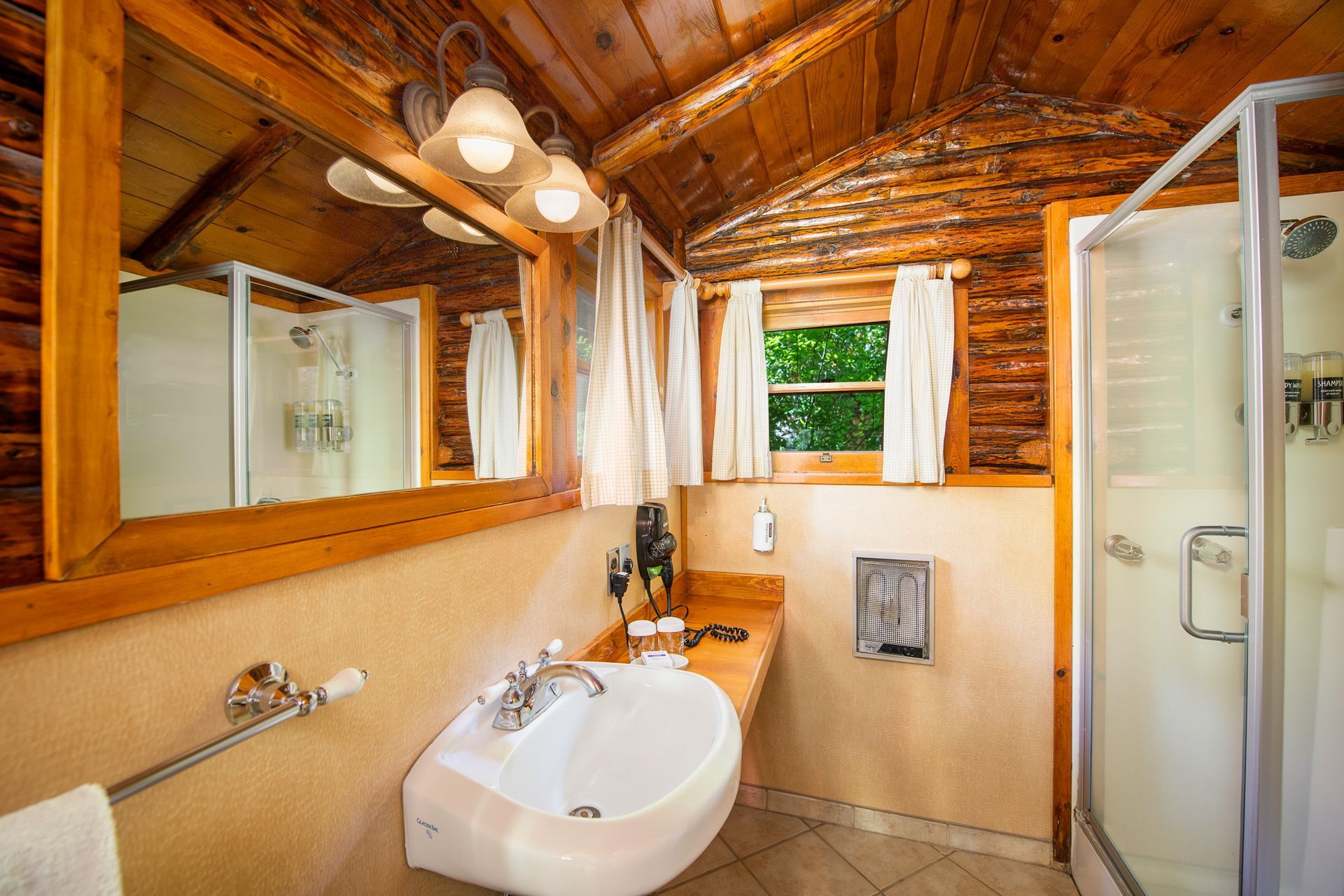 Rustic bathroom with wood paneling, a sink, shower, and a window with curtains.