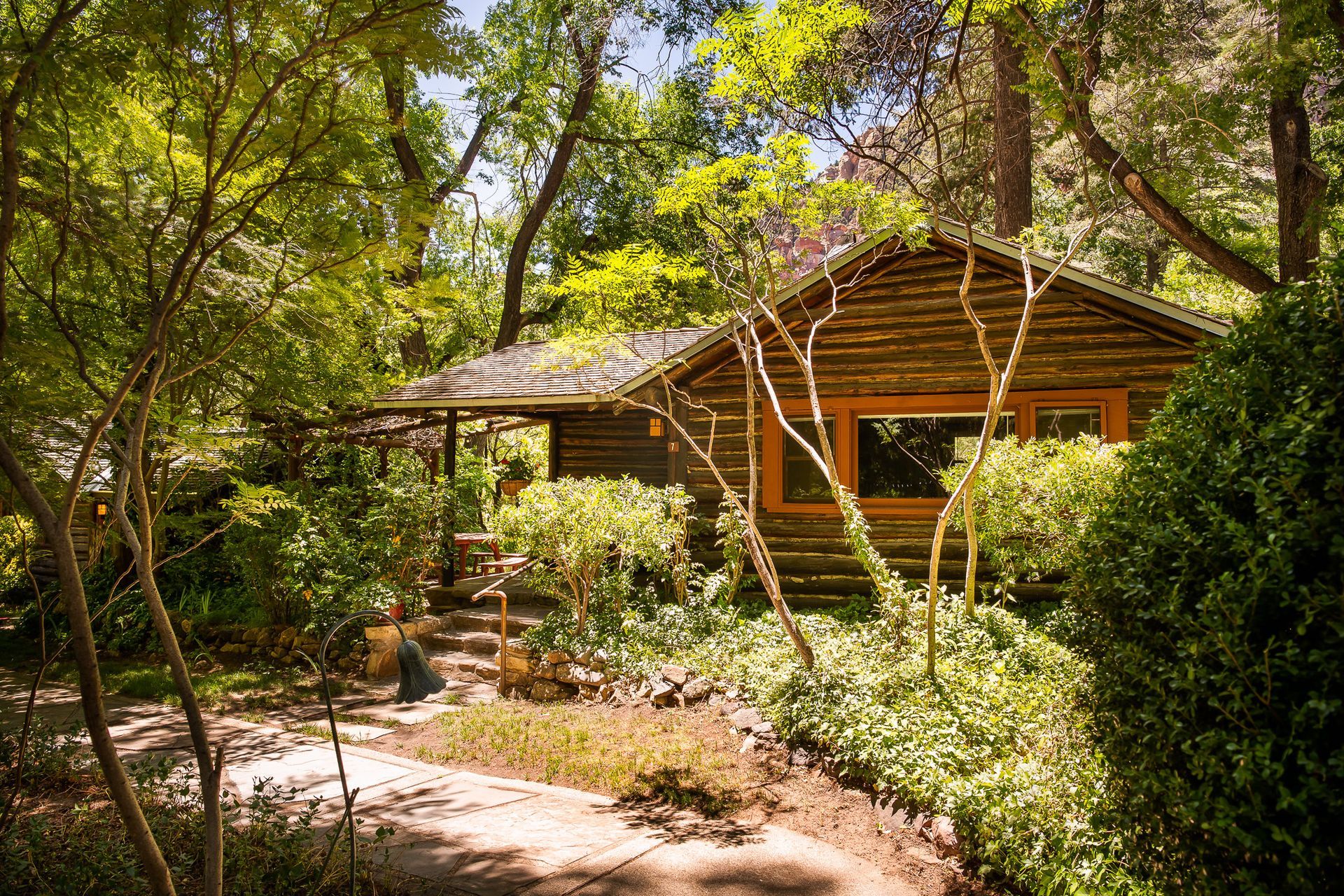 Wooden cabin nestled among lush green trees and vegetation.