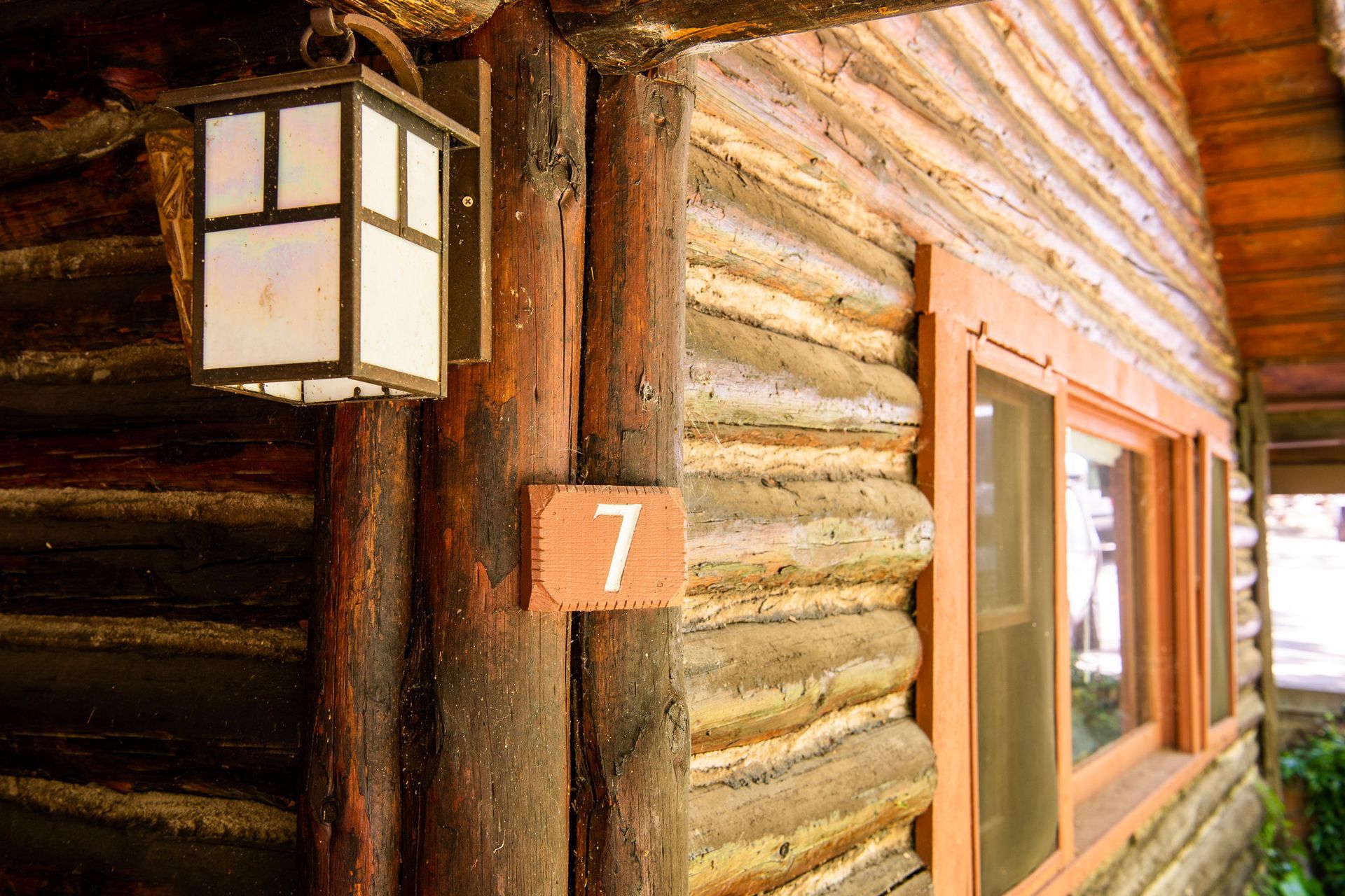 Log cabin corner with the number 7, a window, and a lantern.