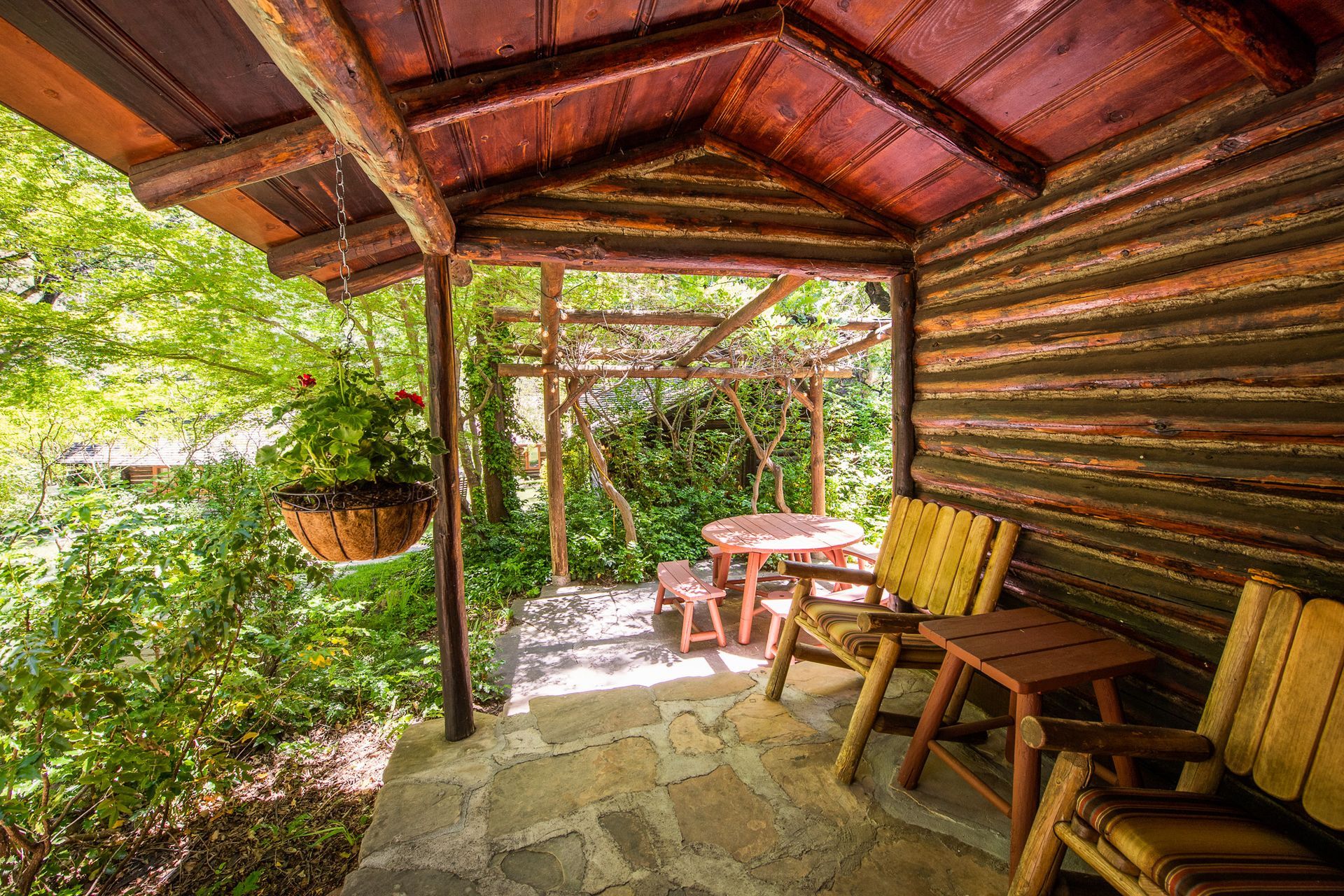 Wooden porch with table and chairs, overlooking a lush green garden.