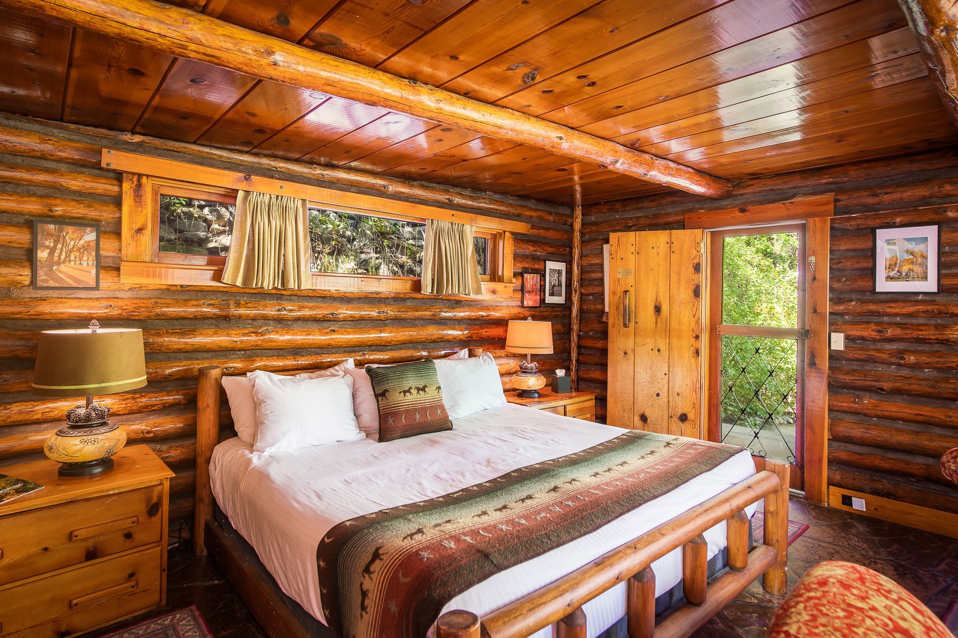 Cozy log cabin bedroom with a double bed, natural wood walls, and a window looking out.