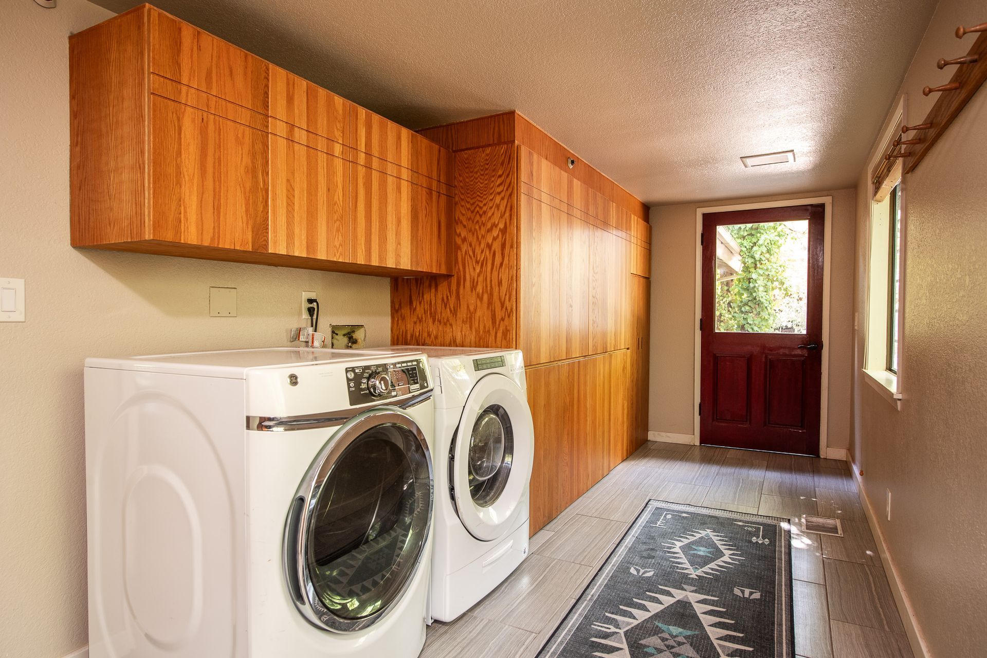 Laundry room with washer/dryer, wooden cabinets, doorway, rug.