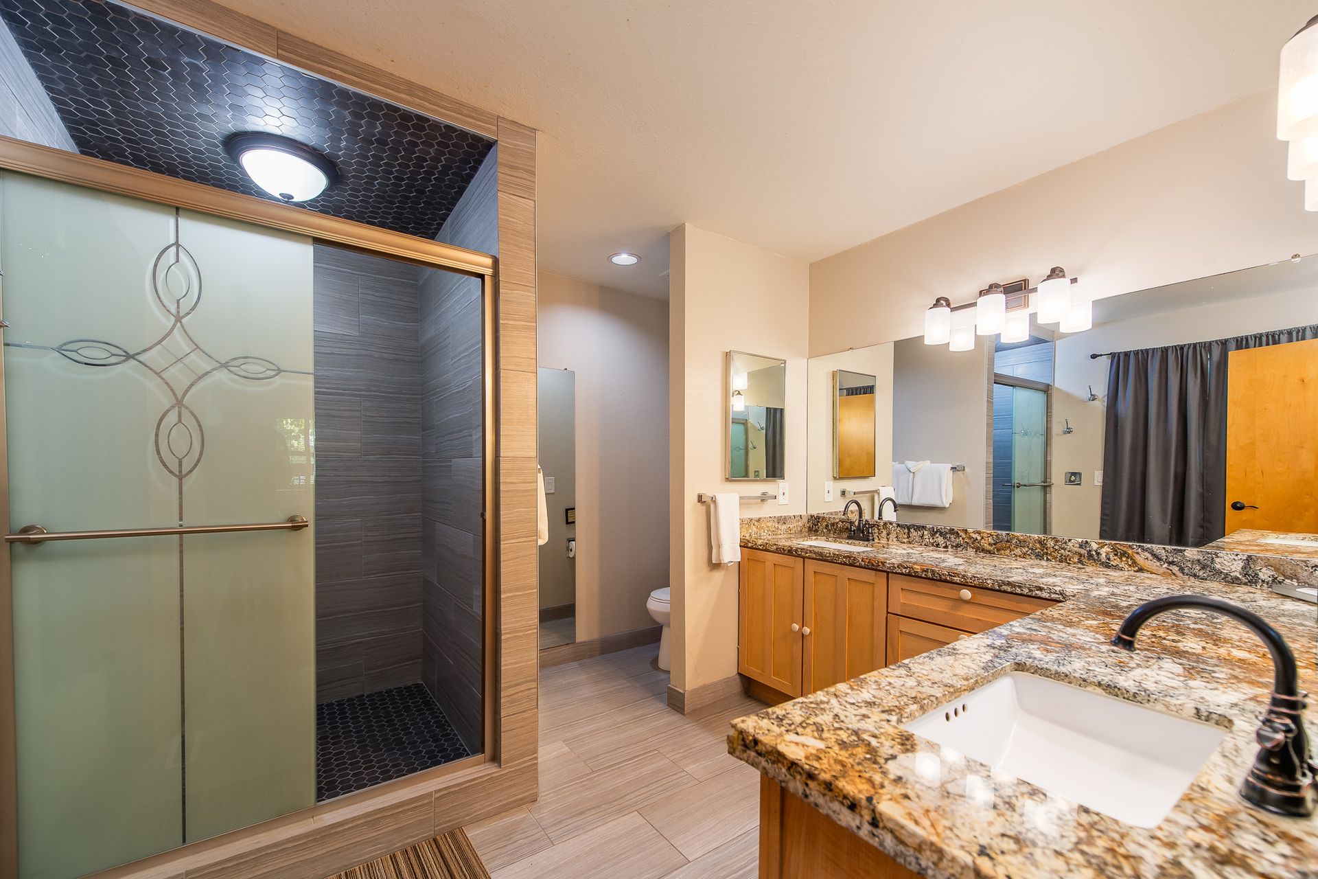 Spacious bathroom with shower, double vanity, toilet, and granite countertops.