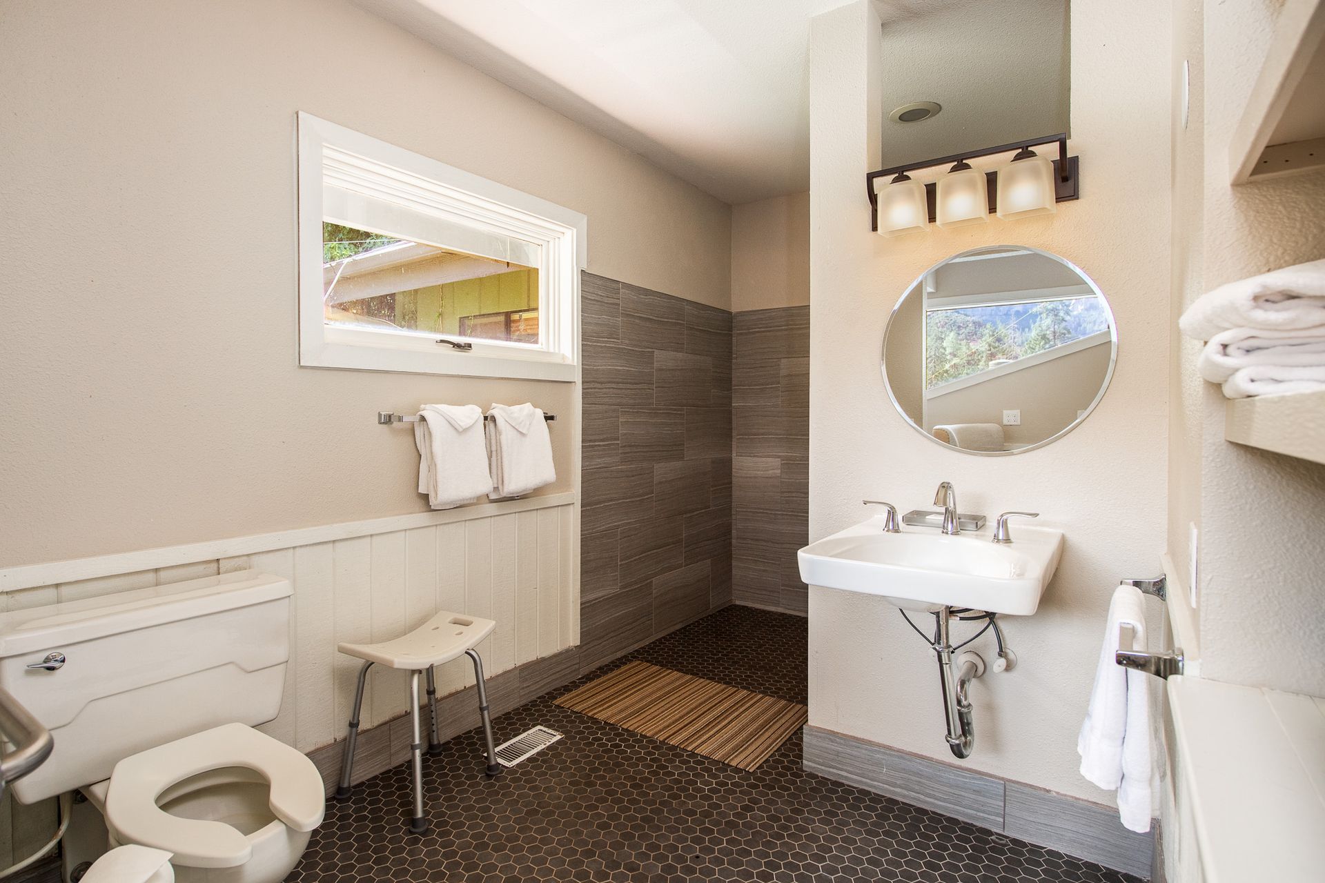 Accessible bathroom: toilet, sink, and shower with grab bars. Neutral color palette.