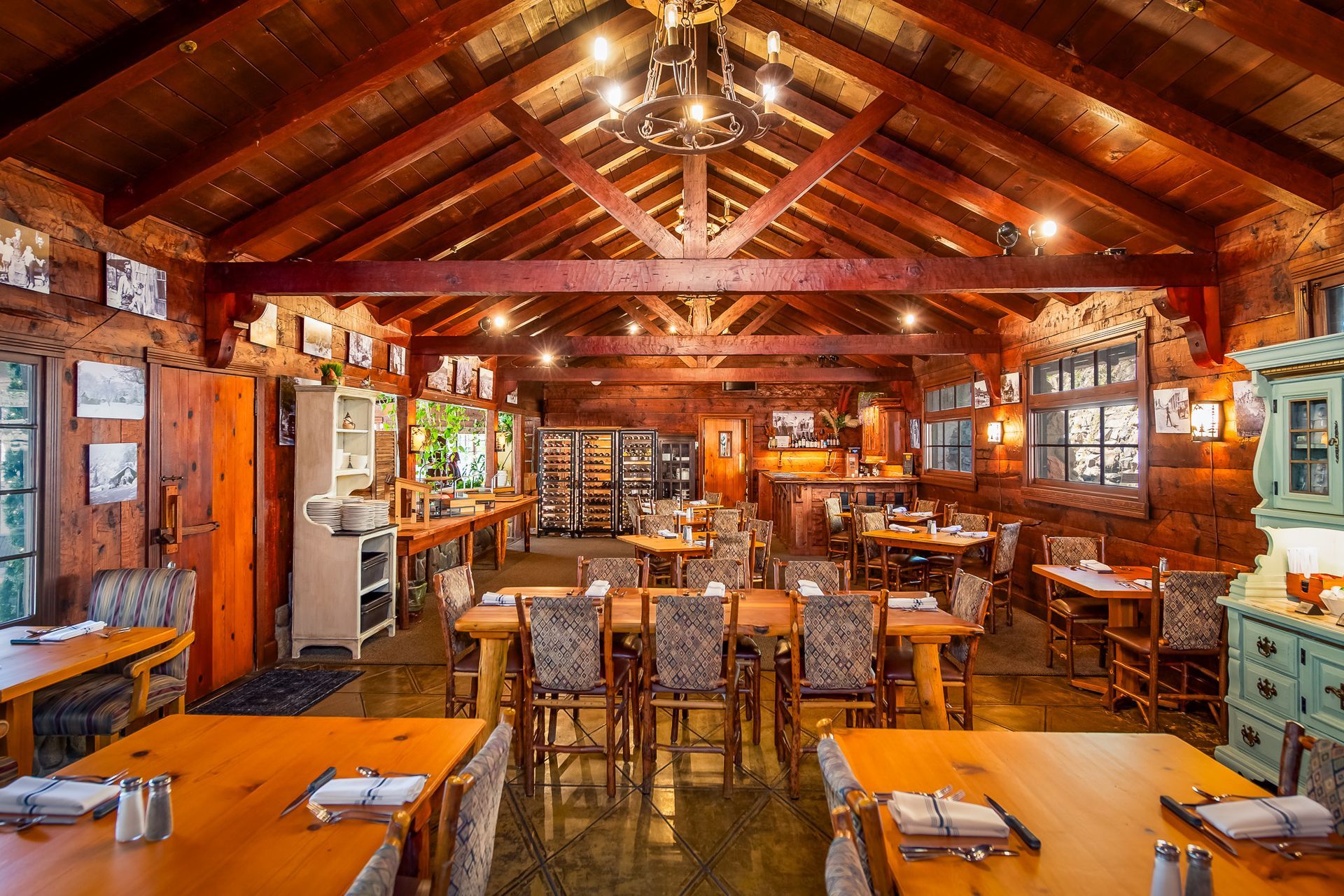 Rustic lodge interior with wood tables, chairs, and walls. Dining area with various seating and lighting.