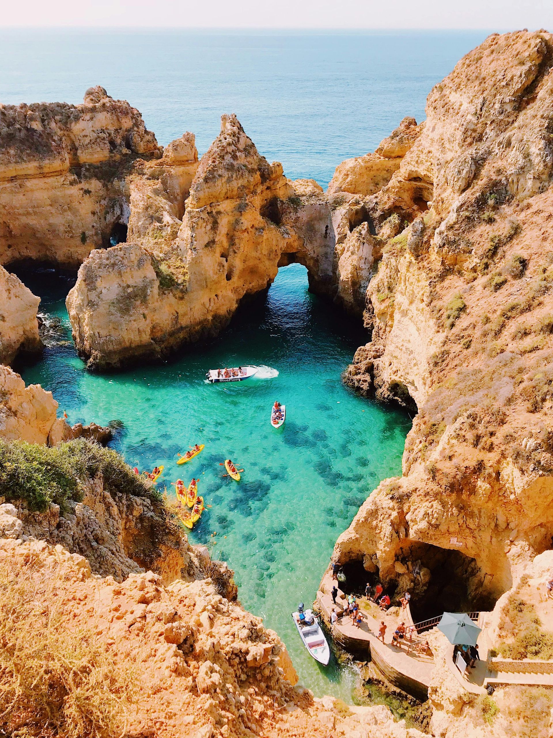 A group of people in kayaks are floating on top of a body of water surrounded by rocks.