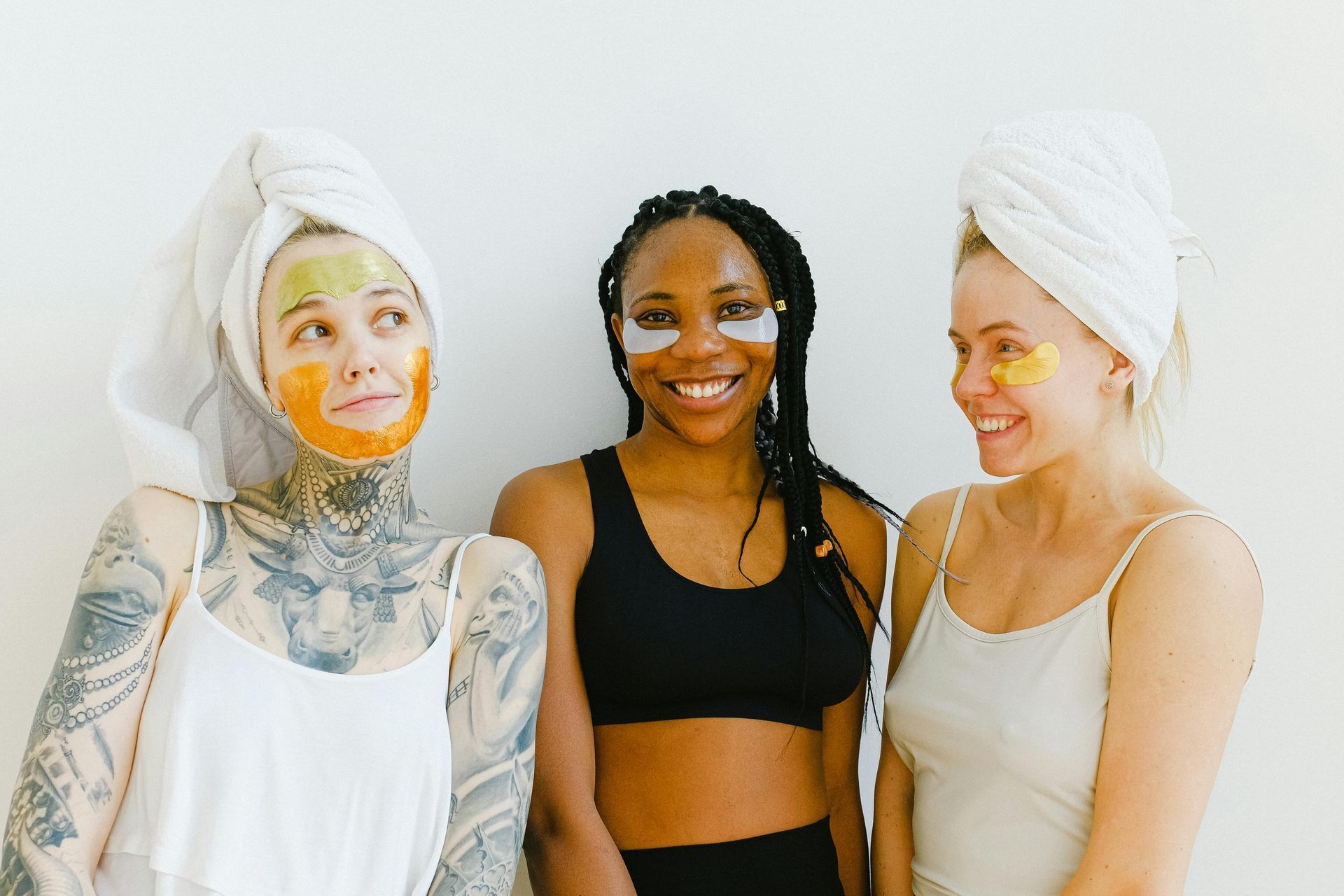 Three women are standing next to each other with facial masks on their faces.