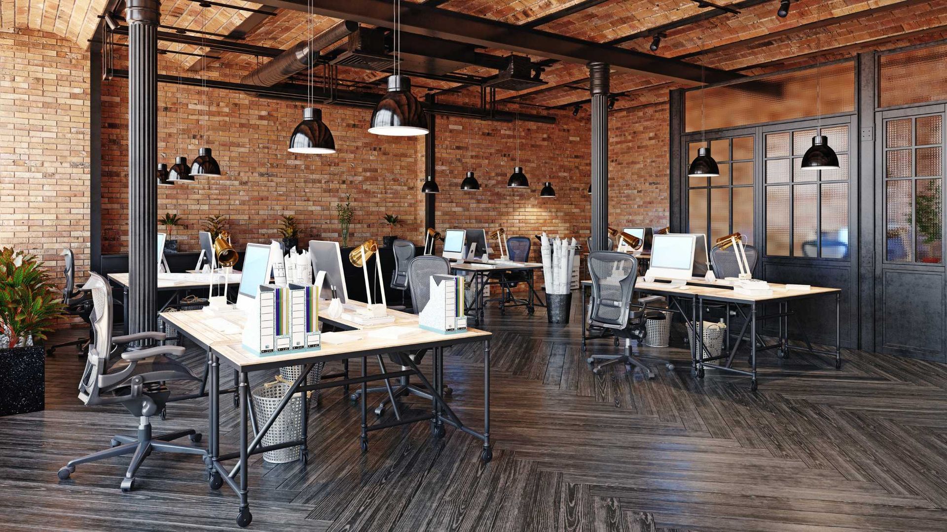 Open-concept office with exposed brick, wooden beams, desks, and hanging pendant lights