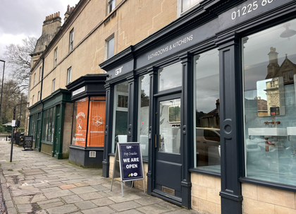 Exterior of a bathroom store with a dark facade, glass windows, and a display of bathroom fixtures.