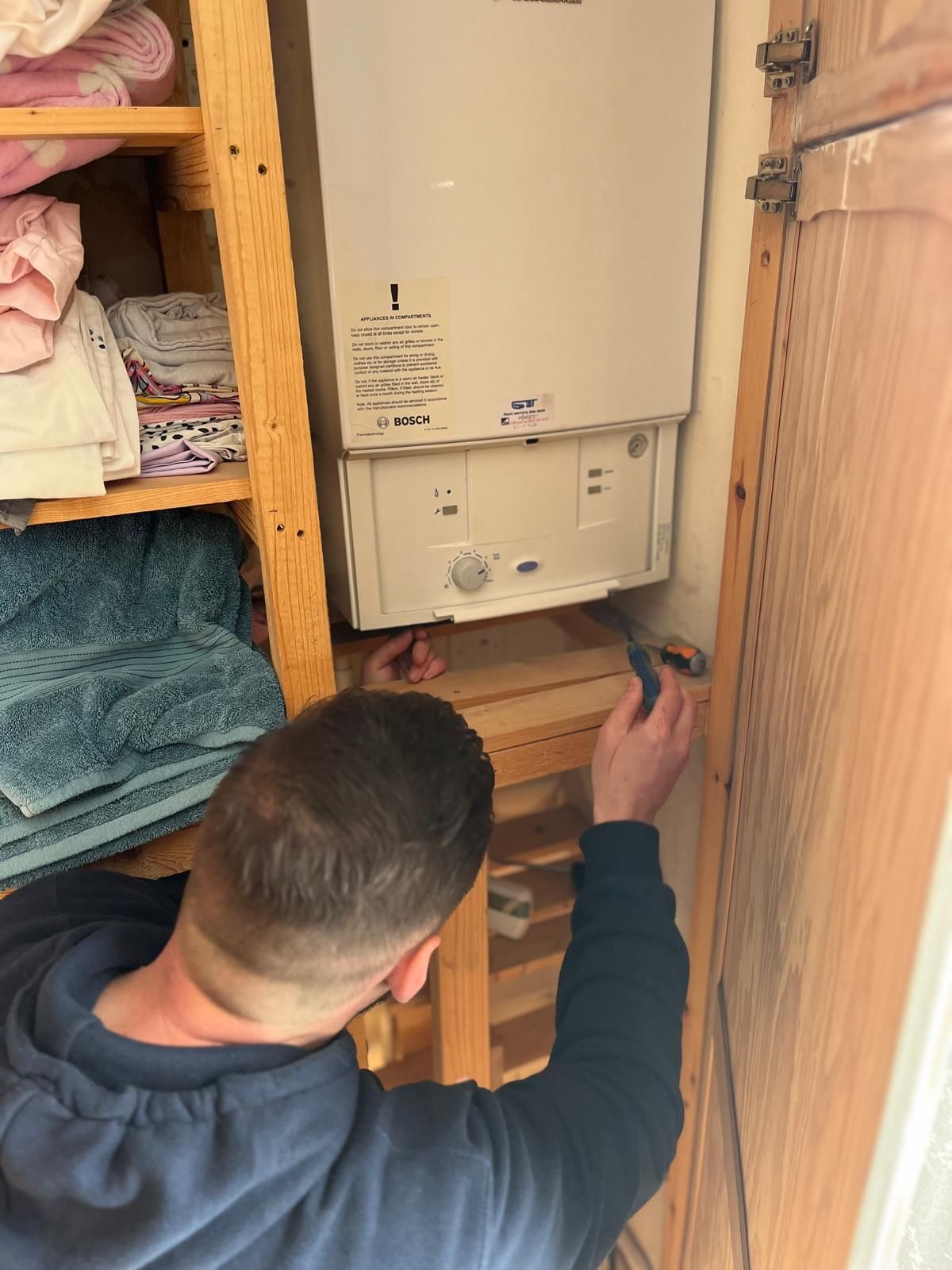 A man is adjusting a thermostat on a wall.