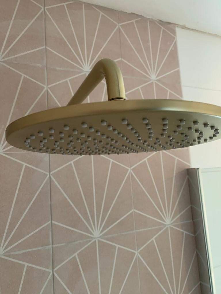 A shower head is hanging from the ceiling in a bathroom.