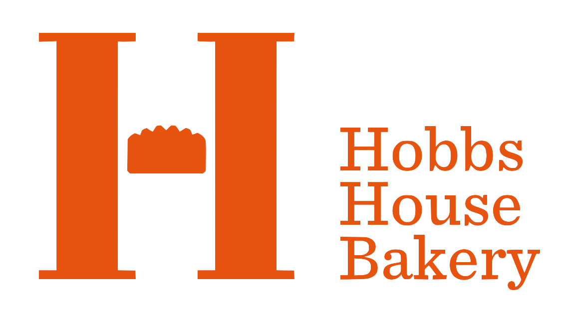 The hobbs house bakery logo is orange and white with a picture of a cake on it.