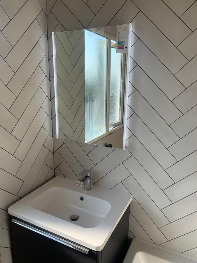A bathroom with a sink , mirror and bathtub.
