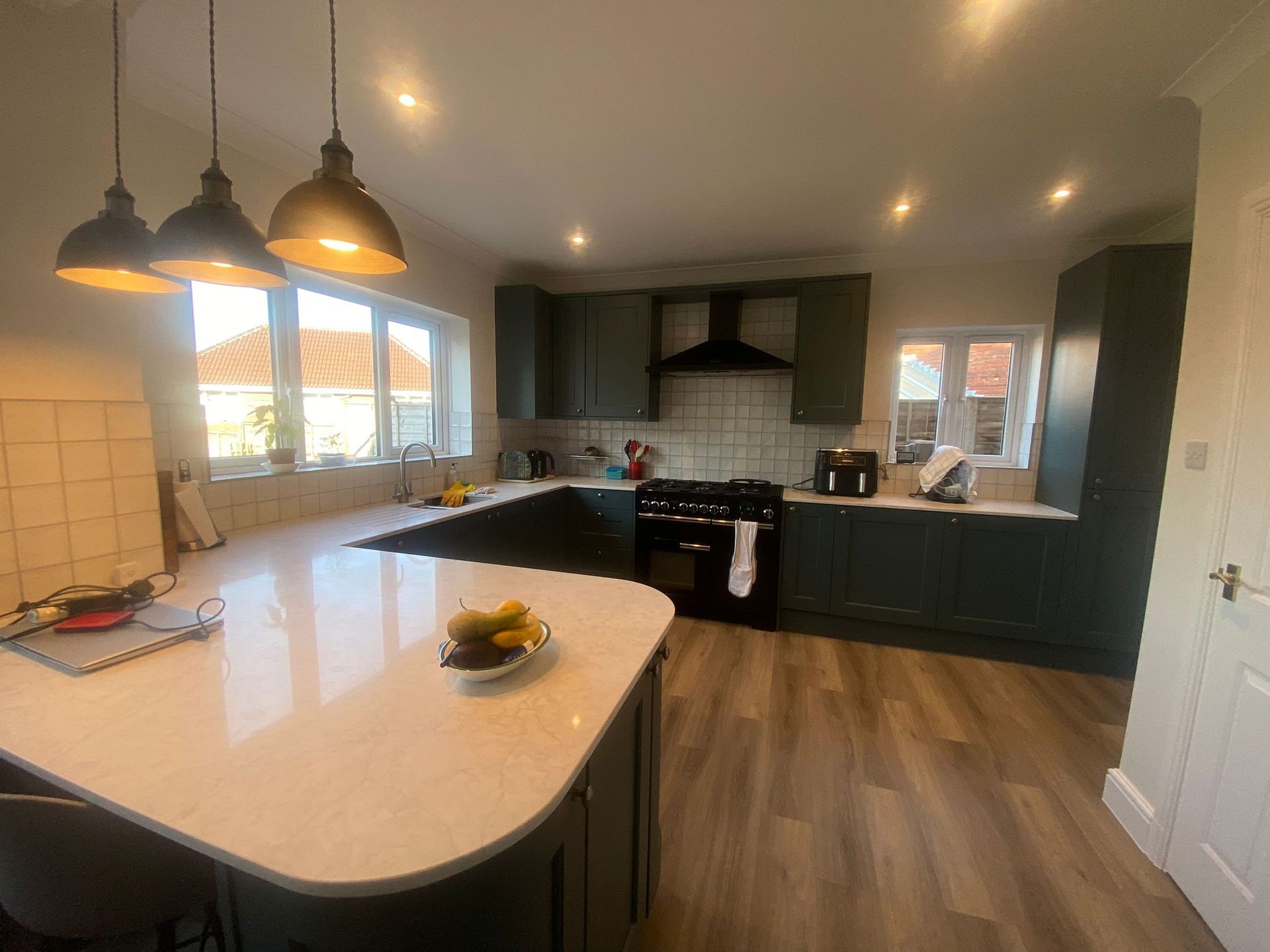 A kitchen with a white counter top , a stove , and a bowl of bananas on the counter.