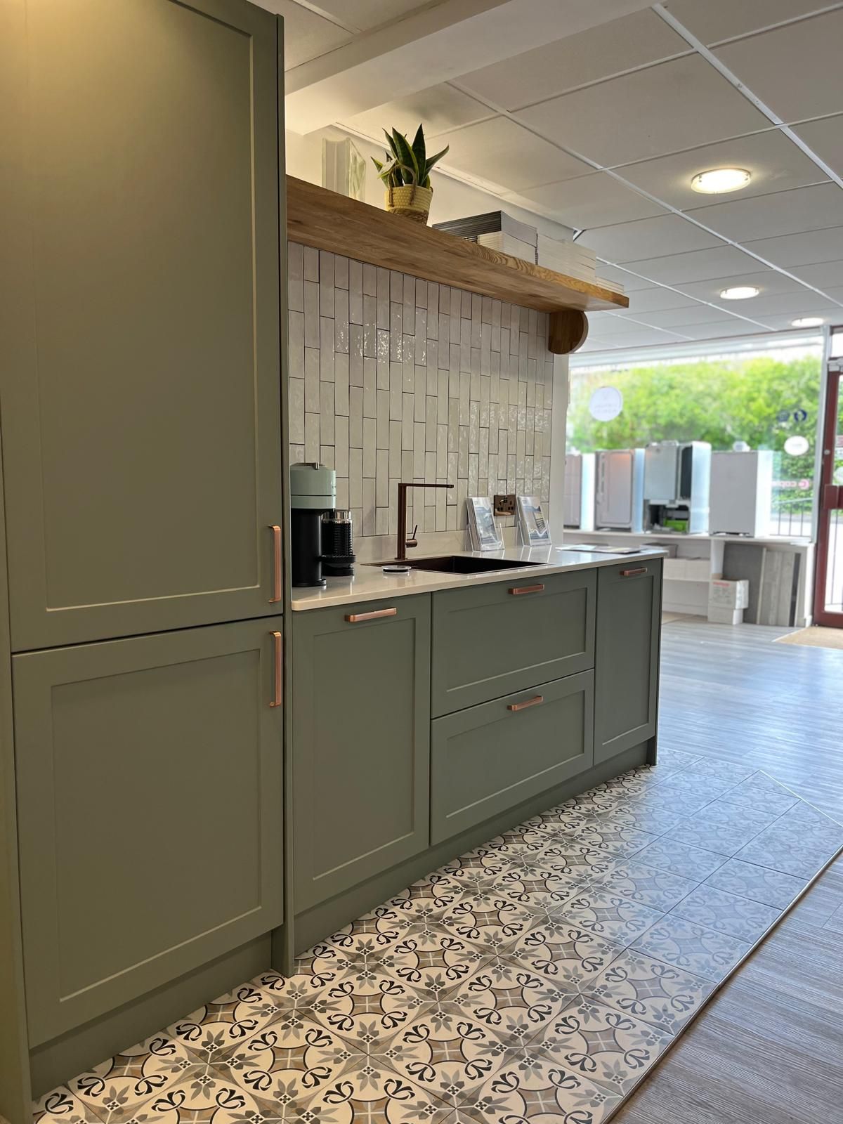A kitchen with green cabinets and a tiled floor.