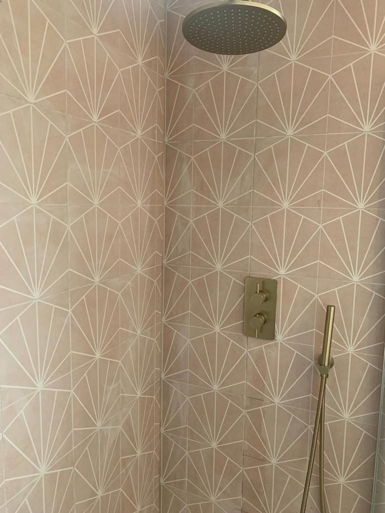 A shower with a geometric pattern on the wall and a shower head.