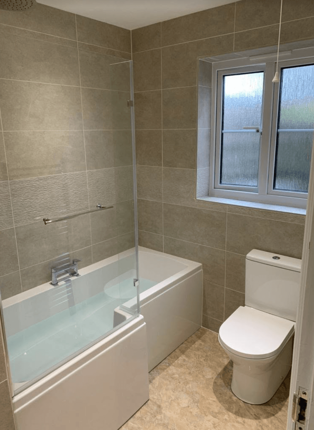 A bathroom with a bathtub , toilet and window.