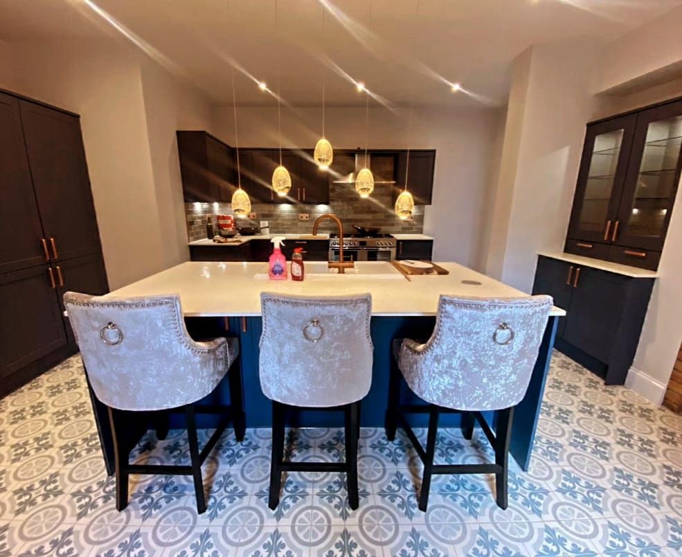 A kitchen with a large island and three chairs.